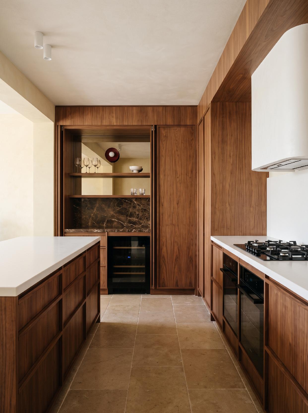 A photograph of a modern and warm kitchen with rich wood finishes and integrated functional design, captured a