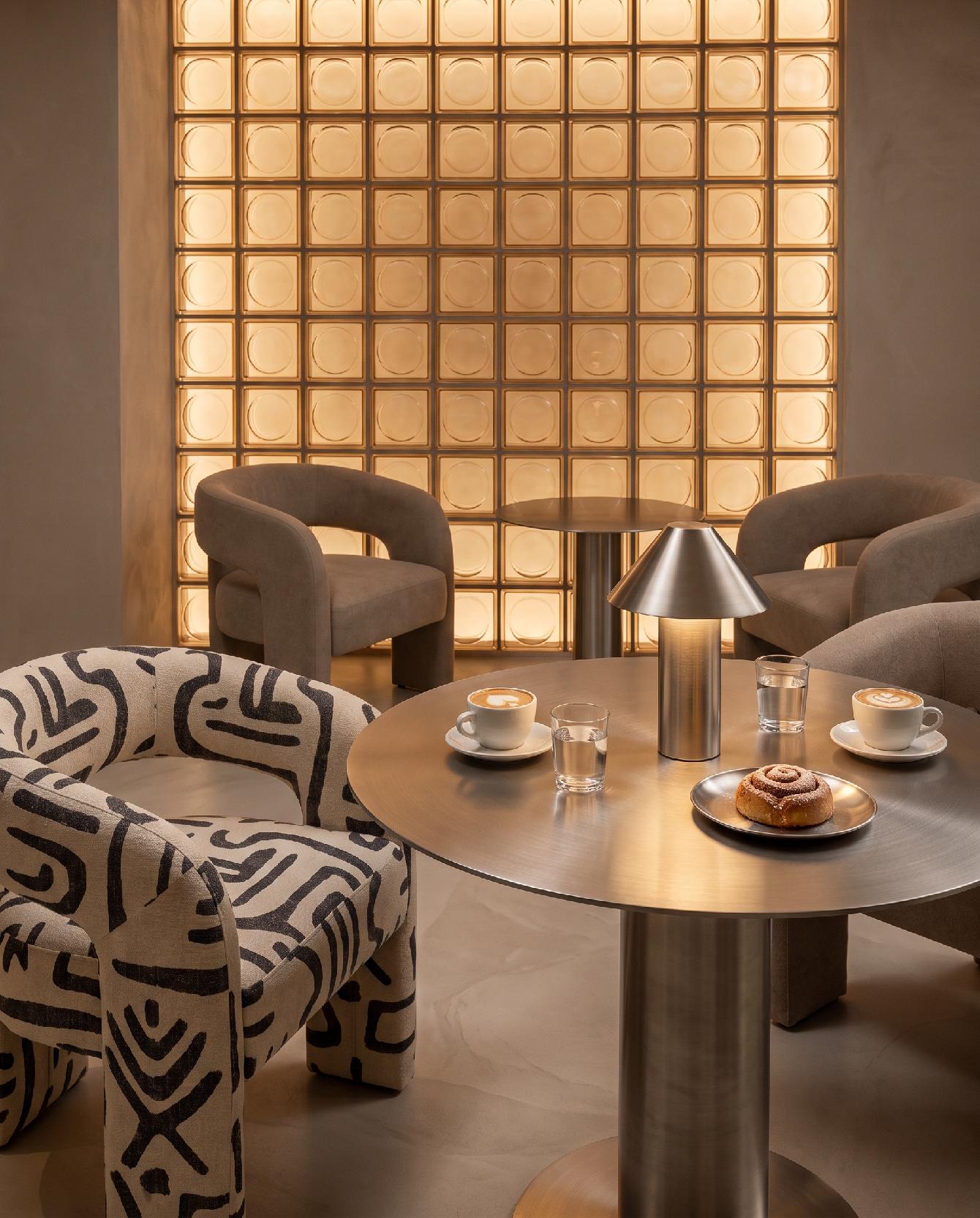 A photograph of a warm and sophisticated modern cafe interior with sculptural furniture and a distinctive back