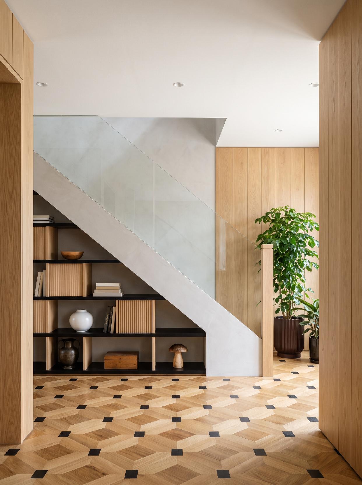A photograph of a modern and minimalist entryway with warm wood tones and a striking geometric floor pattern, 