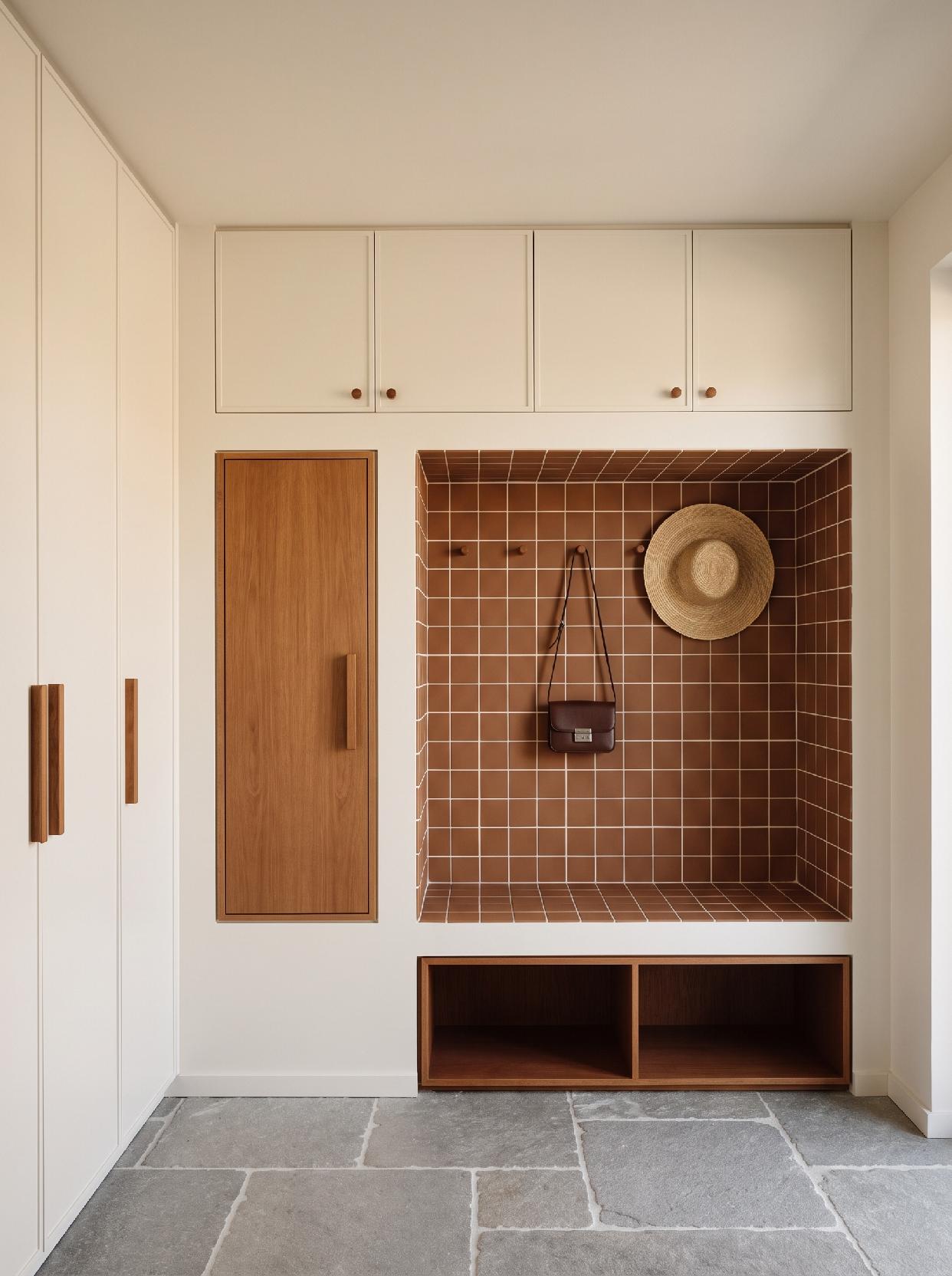 A photograph of a clean and functional modern entryway with warm minimalist aesthetics and integrated storage 