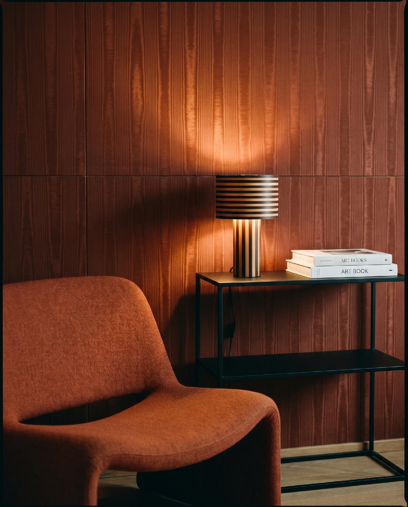 A photograph of a warm and sophisticated contemporary reading nook with rich textures and minimalist furniture
