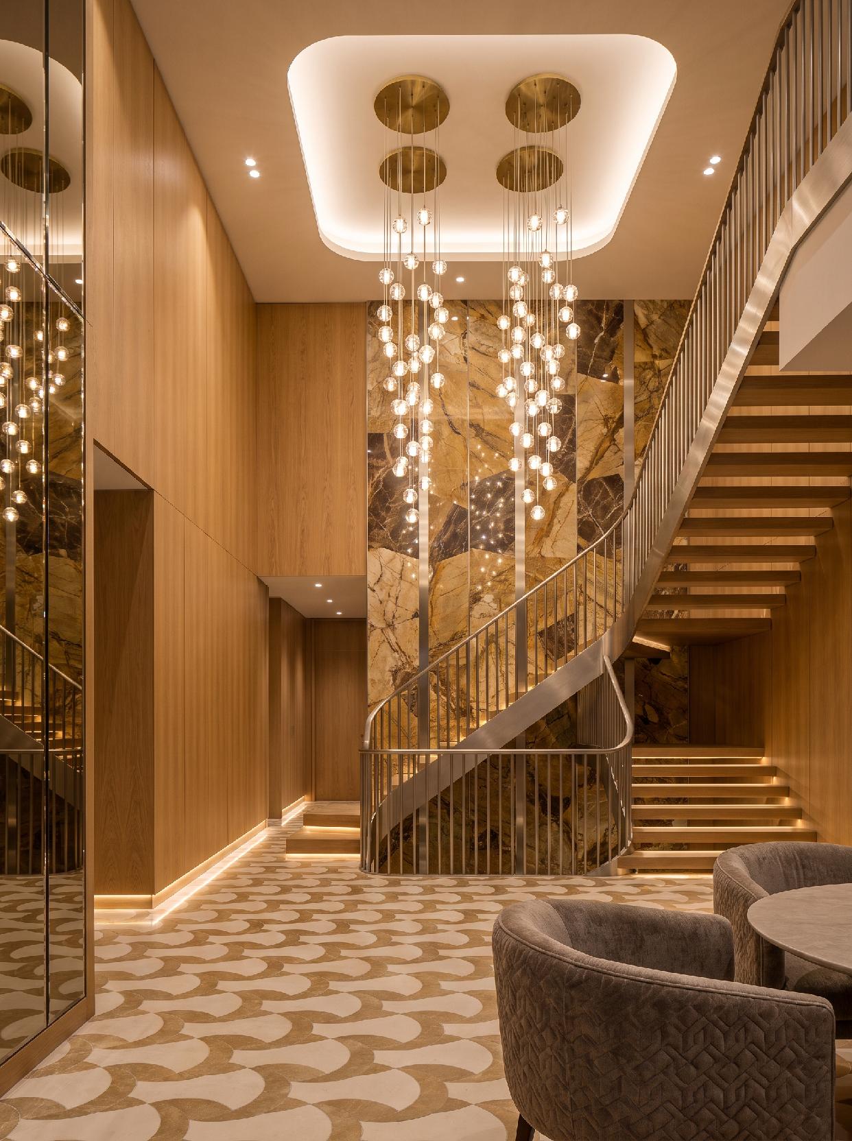 A photograph of a luxurious and sophisticated contemporary entryway with a grand staircase and elegant lightin
