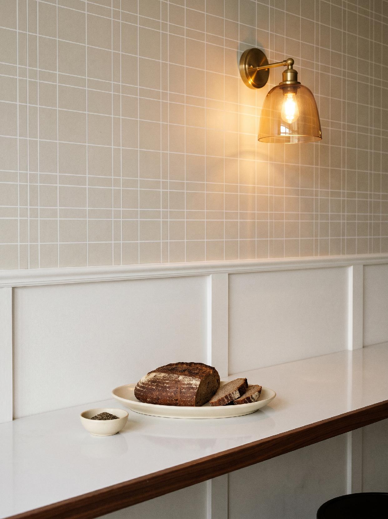 A close-up, eye-level shot of a minimalist counter area, likely in a cafe or kitchen, featuring warm, soft art