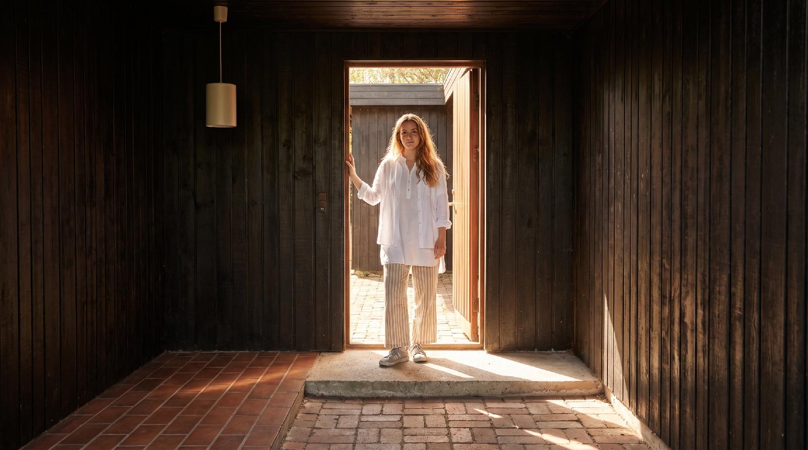 A photograph of a rustic, sunlit entryway with a natural, transitional mood, captured at eye-level with a slig